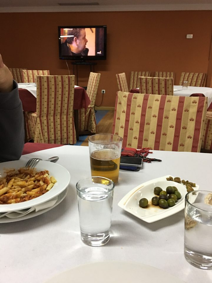 Restaurant mit Essen auf dem Tisch. Im Hintergrund läuft ein Fernseher