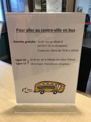 Aufsteller an einer Rezeption beschreibt Busverbindungen in die Stadt in französischer Sprache
